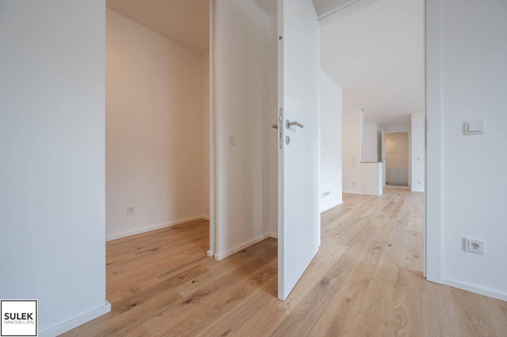 Heller Flur mit Holzboden und offenen Türen, die zu verschiedenen Räumen führen.