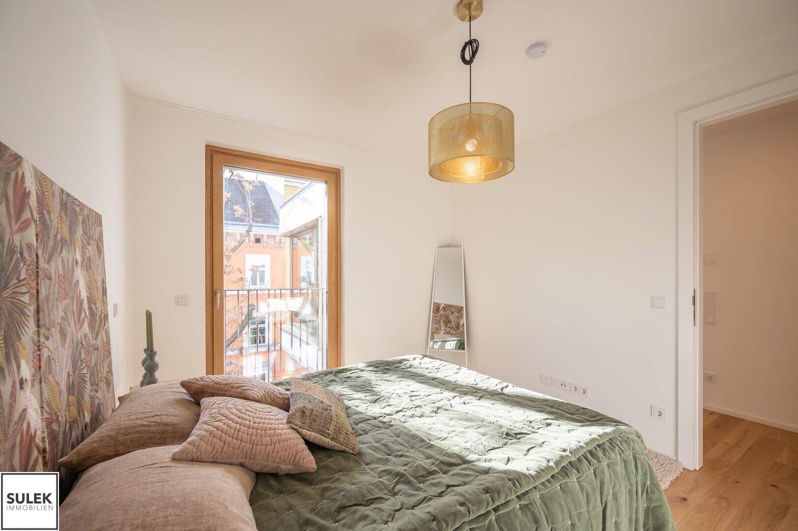 Schlafzimmer mit Holzboden, großem Bett und Fenster mit Blick auf die Stadt.