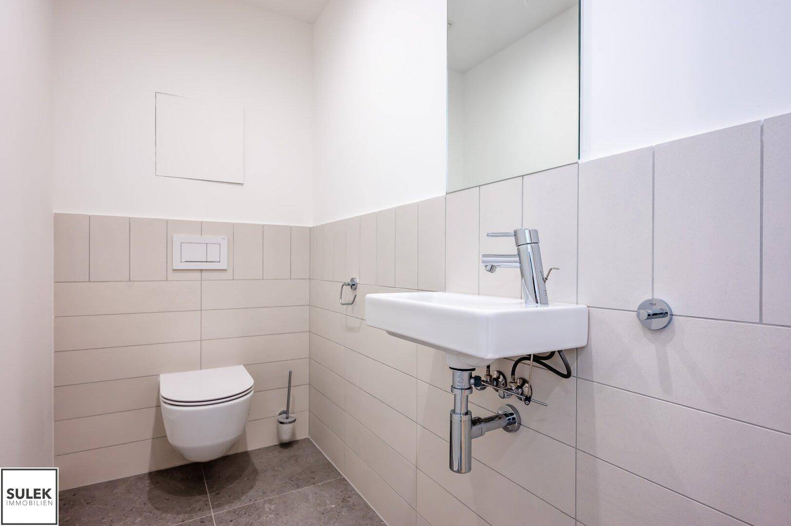 Modernes Gäste-WC mit wandhängender Toilette und kleinem Waschbecken.