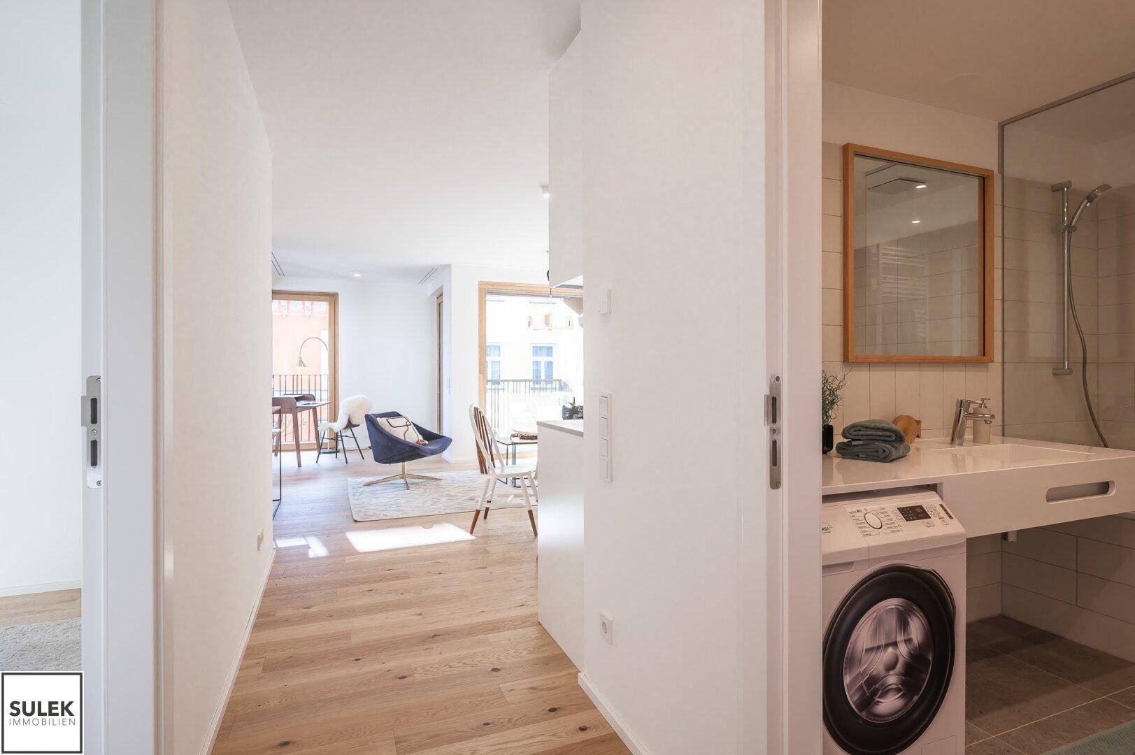 Flur mit Blick auf den offenen Wohnbereich und das moderne Badezimmer.