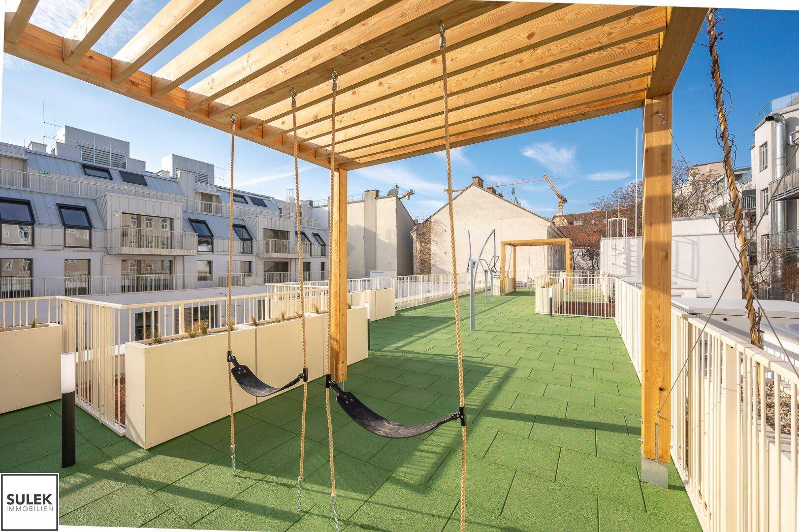 Dachterrasse mit Spielplatz, Schaukeln und Pergola für Kinder.