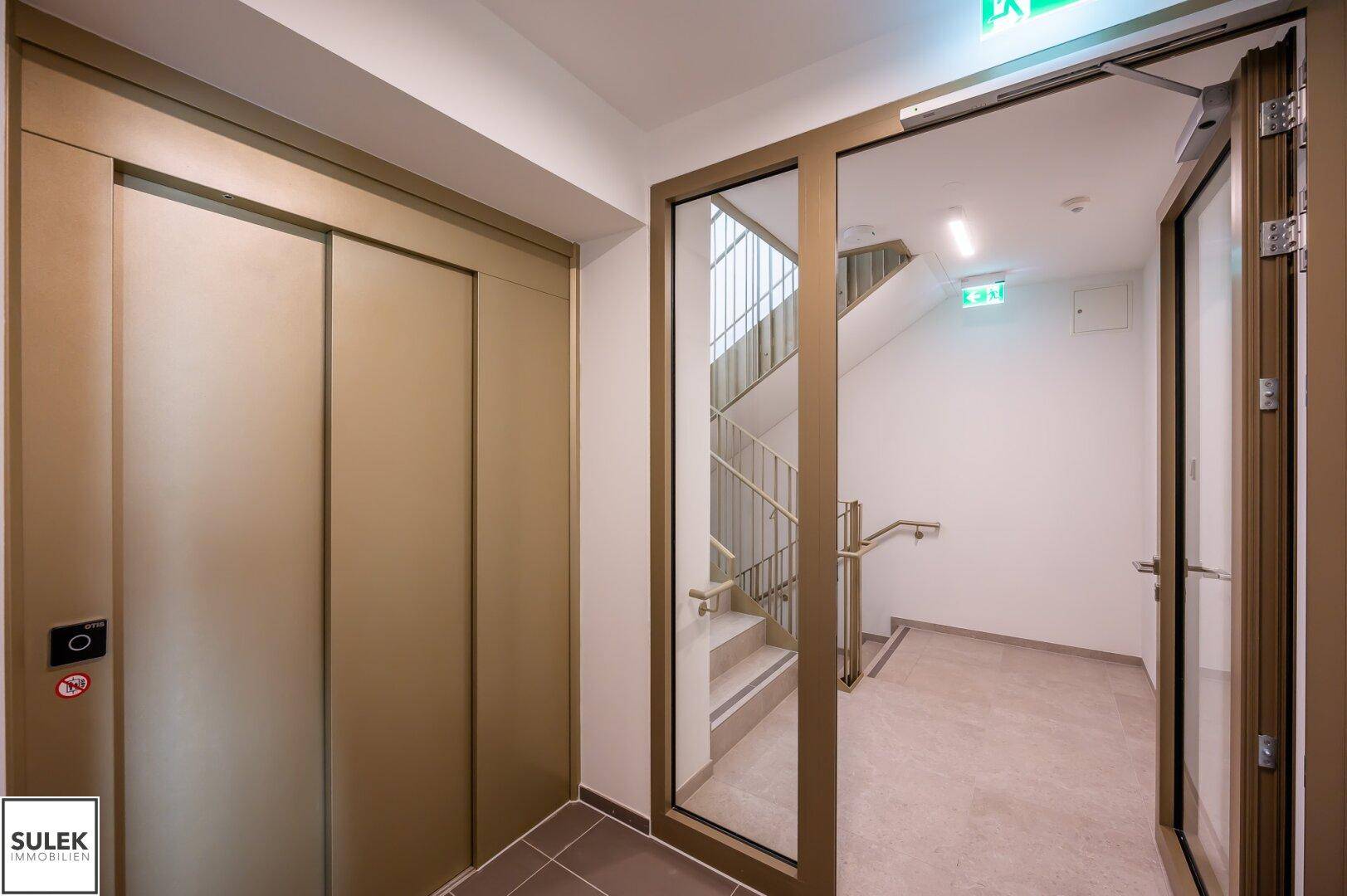 Heller Flur mit modernem Aufzug und Zugang zum Treppenhaus.