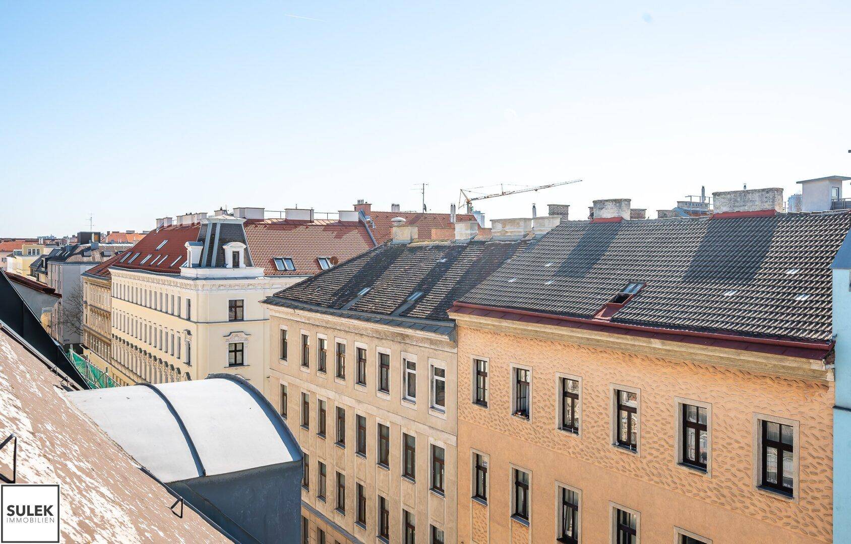 Weitläufiger Blick über die Dächer der Stadt mit verschiedenen Gebäuden und klarem Himmel.