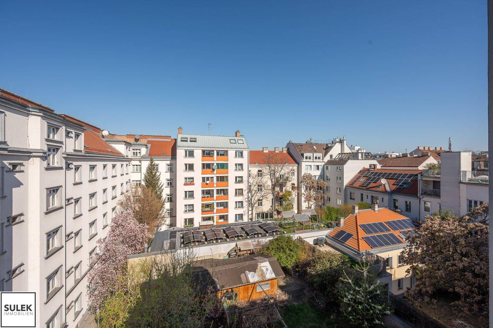 Stadtansicht mit Wohngebäuden, Gärten und Solaranlagen auf einigen Dächern.