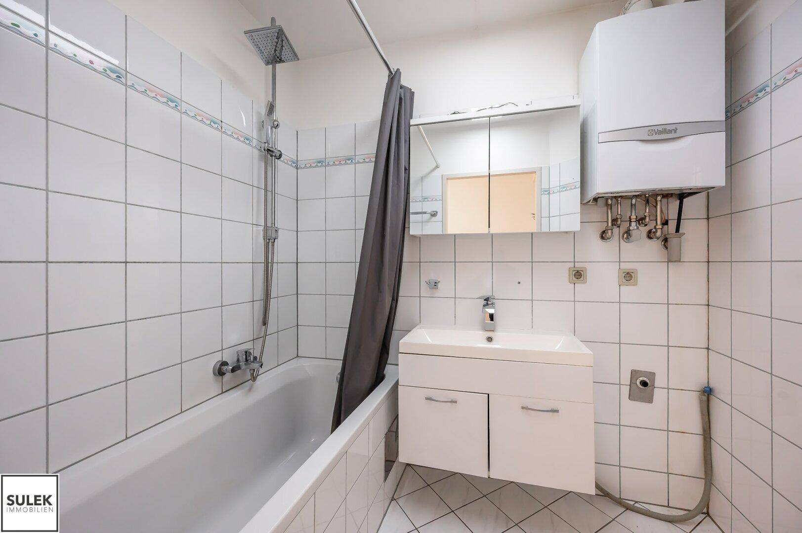 Badezimmer mit Badewanne, Dusche und Waschbecken in weiß gefliestem Raum.