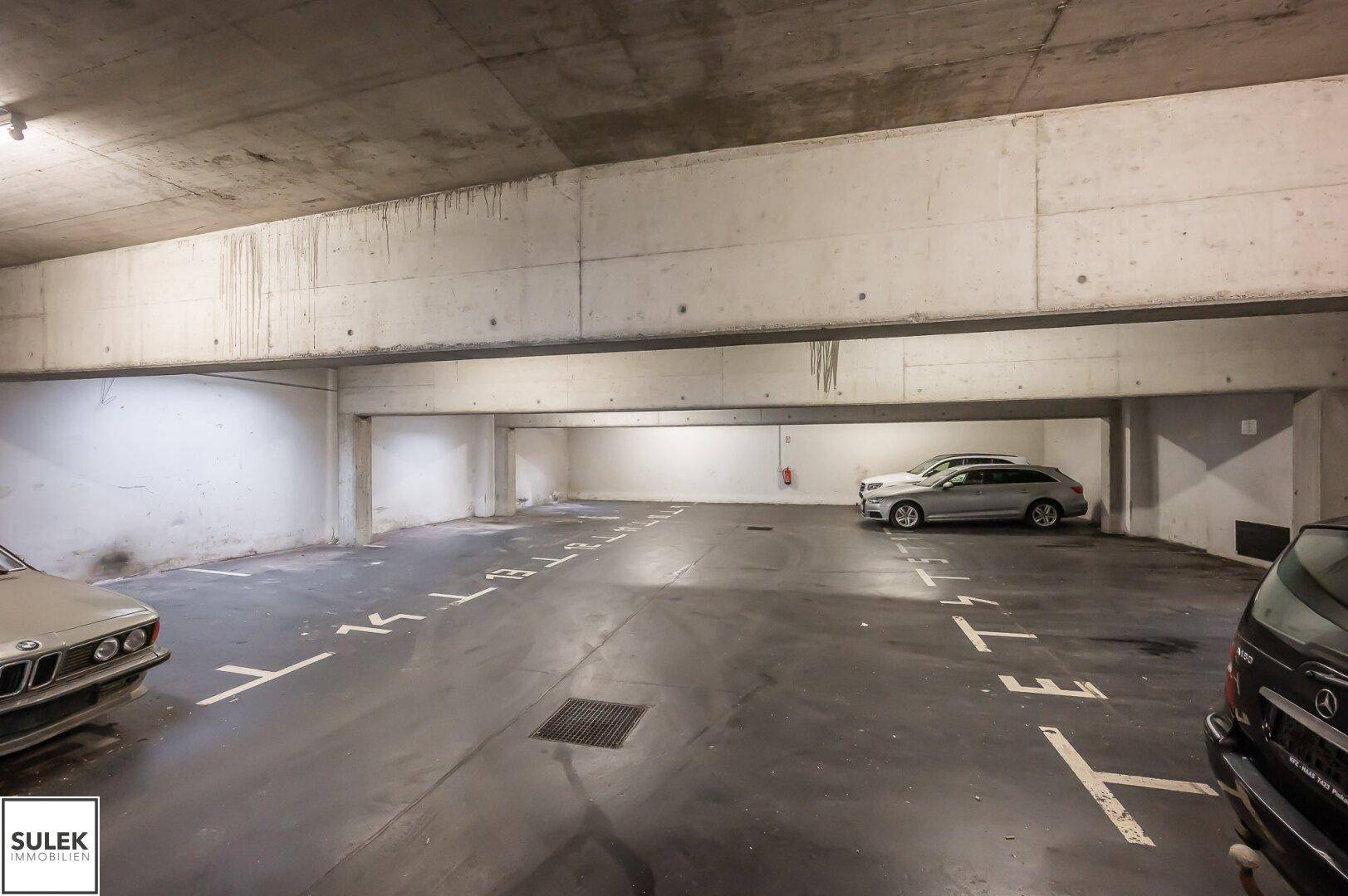 Tiefgarage mit mehreren Stellplätzen und Betonwänden.