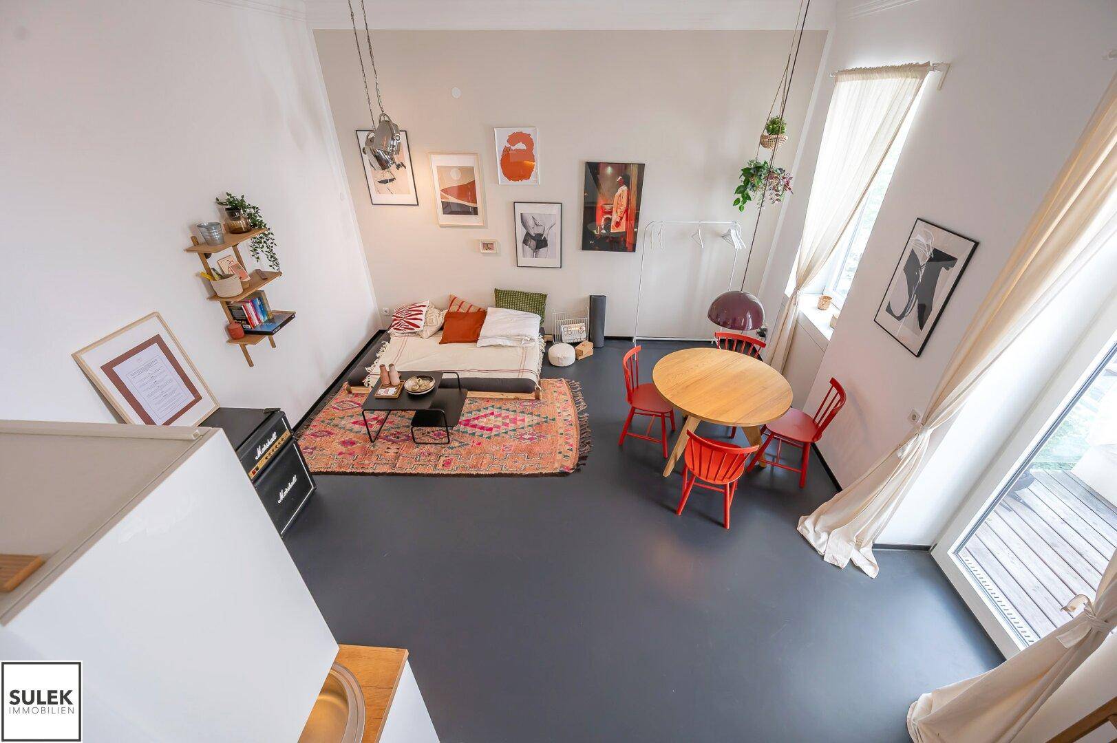 Weitläufiger Blick auf den offenen Wohn-Essbereich mit Hochbett, Sofa und Esstisch von oben.