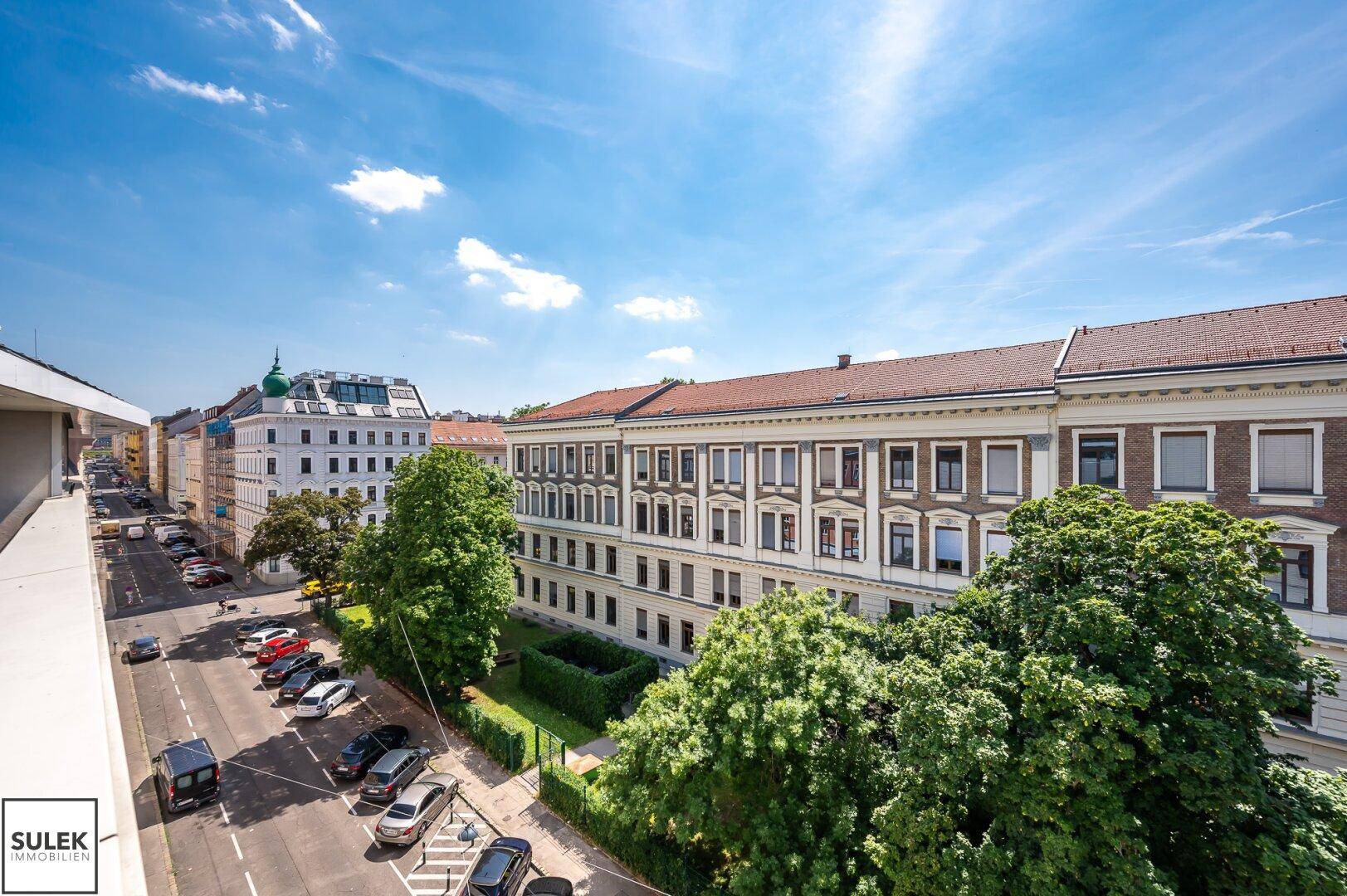 Weitläufiger Blick von der Terrasse auf die Stadtlandschaft mit historischen Gebäuden und grünen Alleen.