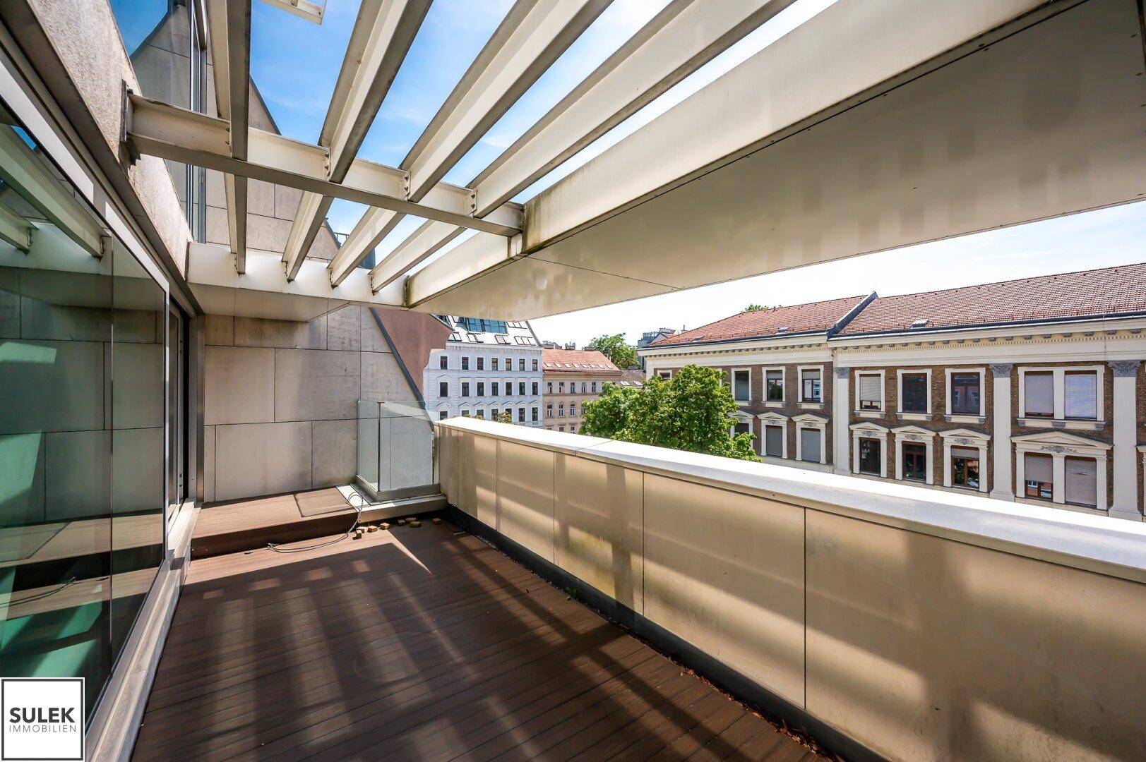 Überdachte Terrasse mit Holzboden, Metallkonstruktion und weitem Blick über die Stadt.