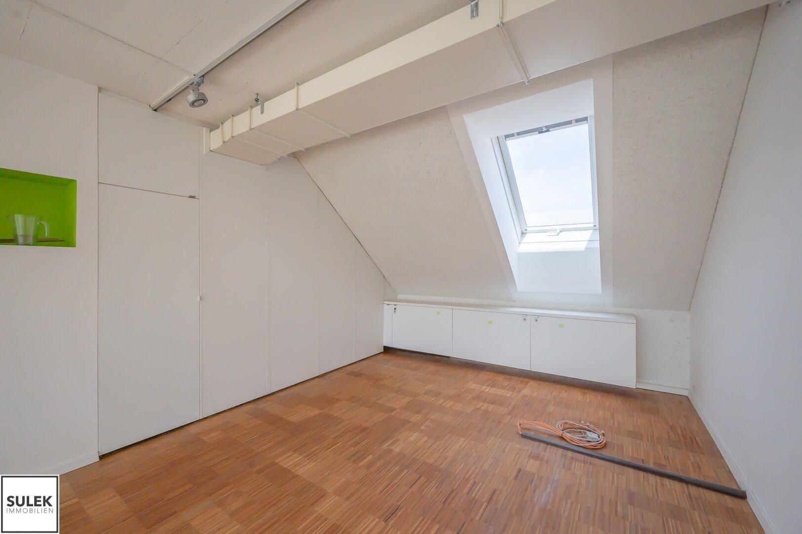 Dachgeschossbüro mit schrägen Wänden, Dachfenster und Einbauschränken, bietet eine ruhige Arbeitsatmosphäre.
