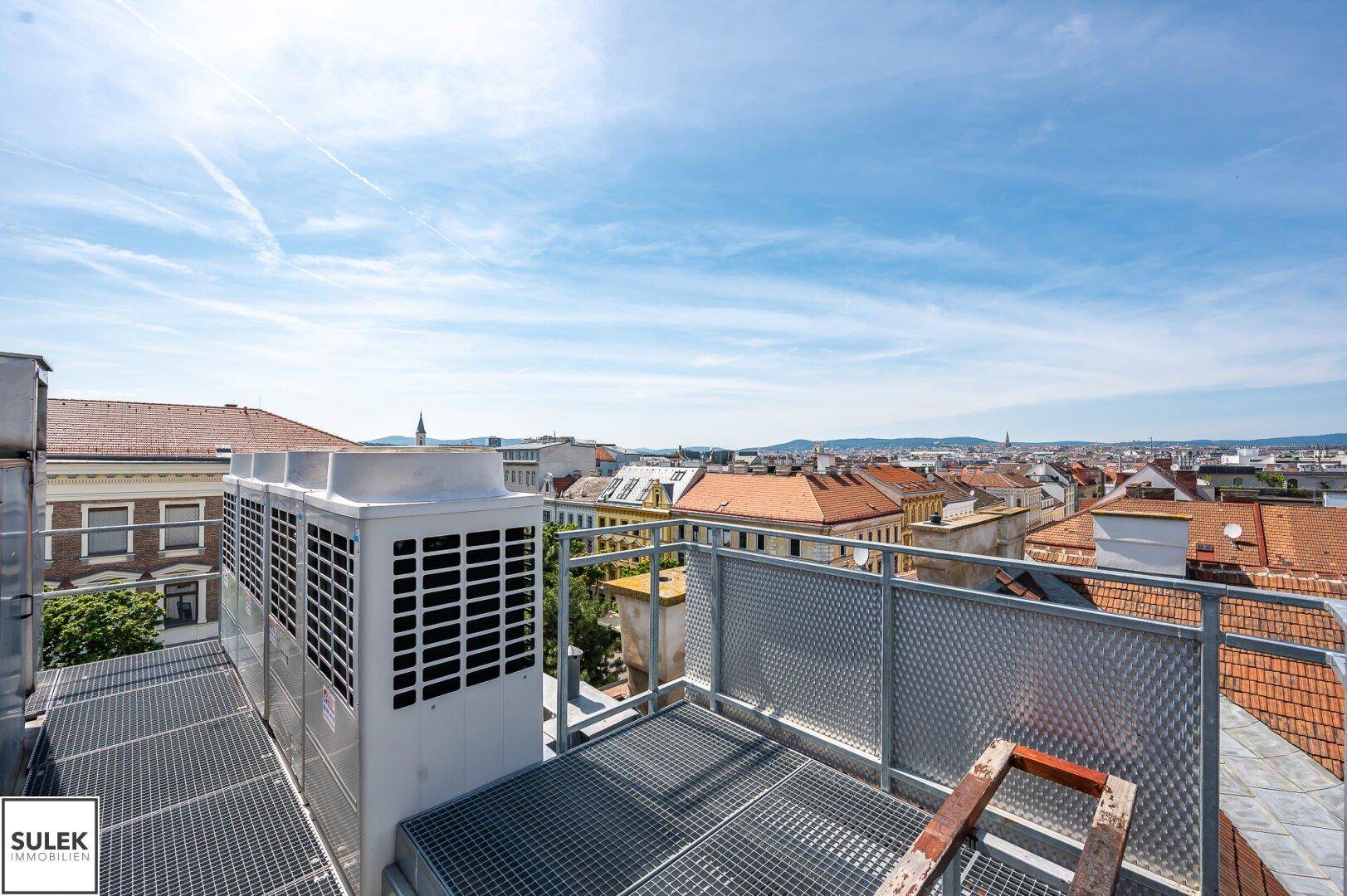 Dachbereich mit Klimaanlagen und Metallgittern, bietet einen weiten Blick über die Stadt.