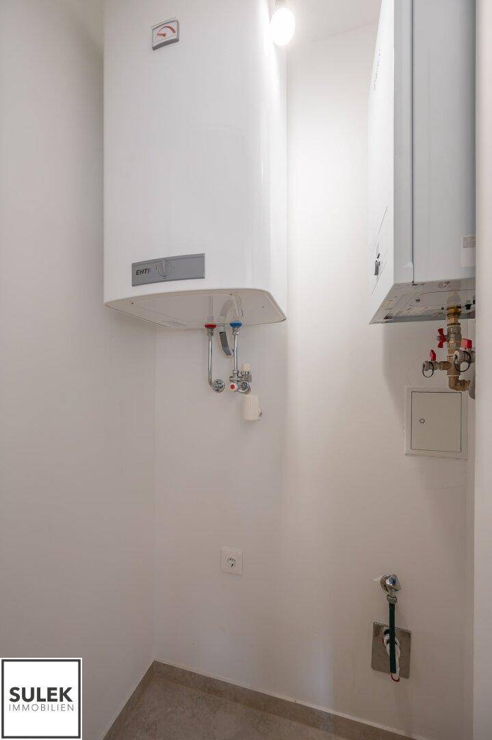 Hauswirtschaftsraum mit zwei an der Wand montierten Warmwasserbereitern und Anschlüssen.