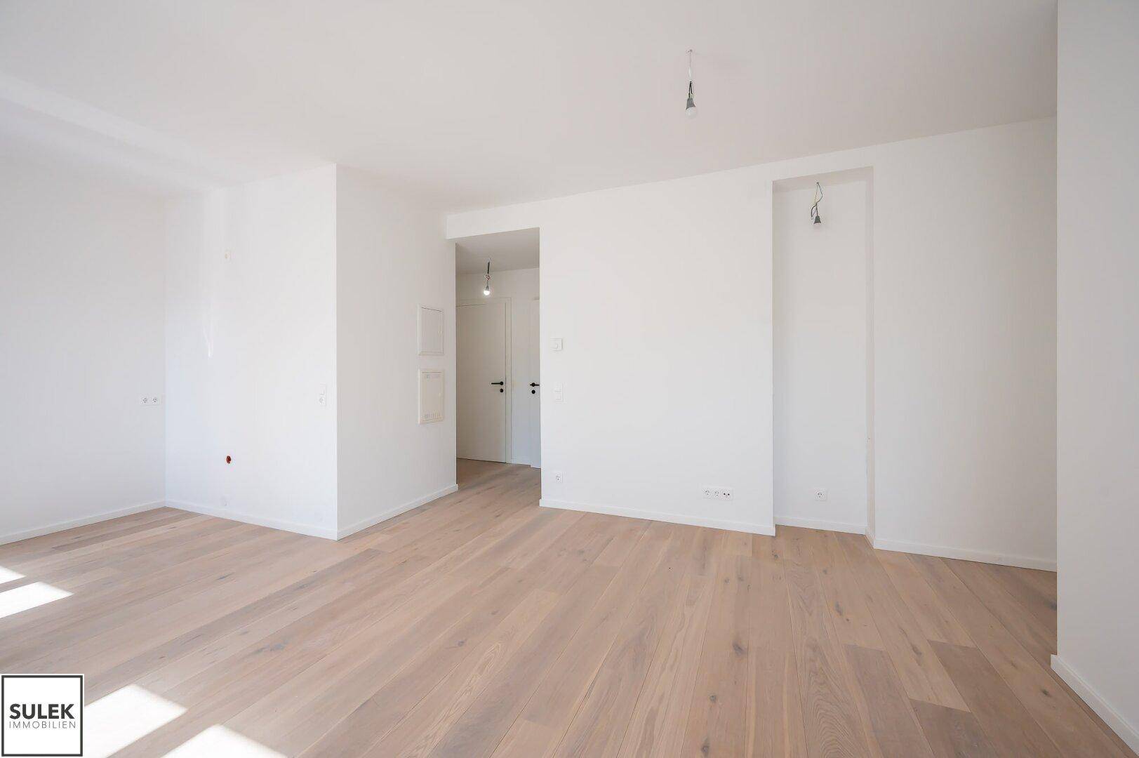 Heller Raum mit Holzboden und einer Wandnische, die vielseitig genutzt werden kann.