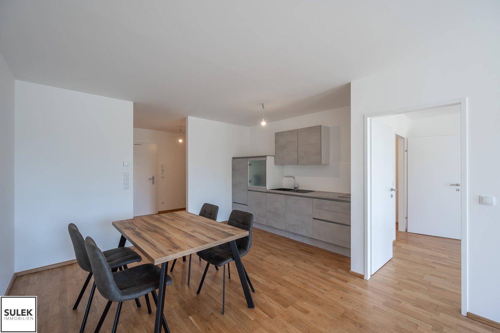 Moderner Wohn-Essbereich mit integrierter Küchenzeile und Holzboden.