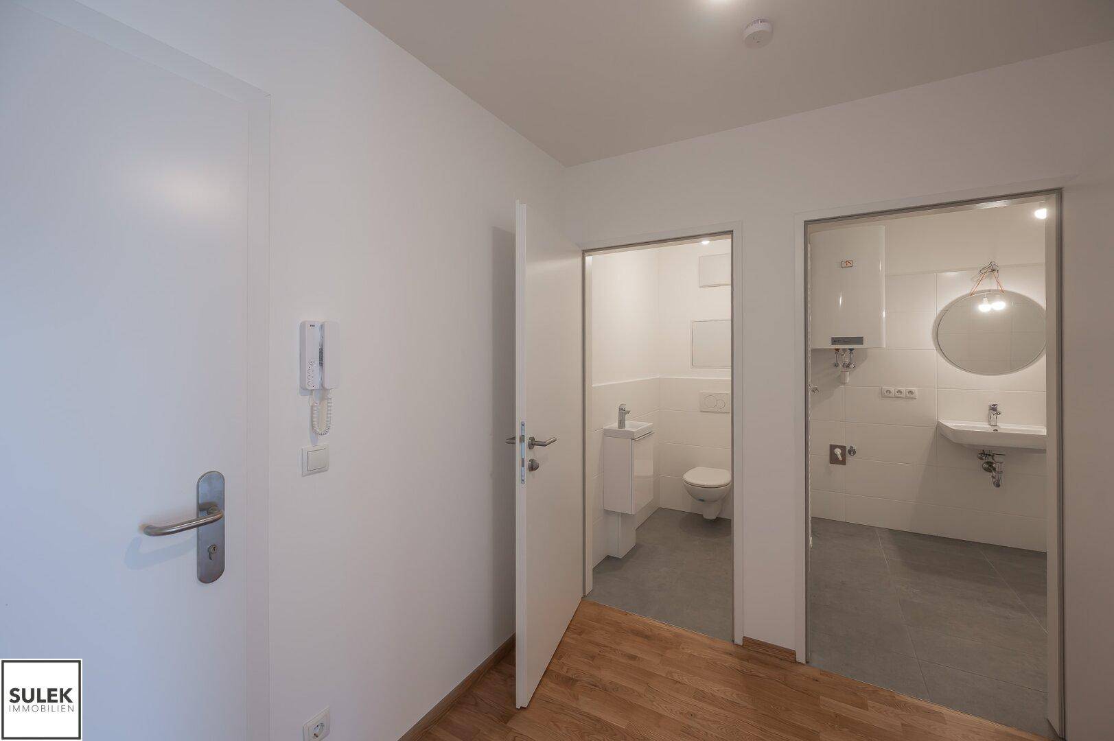 Flur mit Holzboden und Zugang zu separatem WC und modernem Badezimmer.