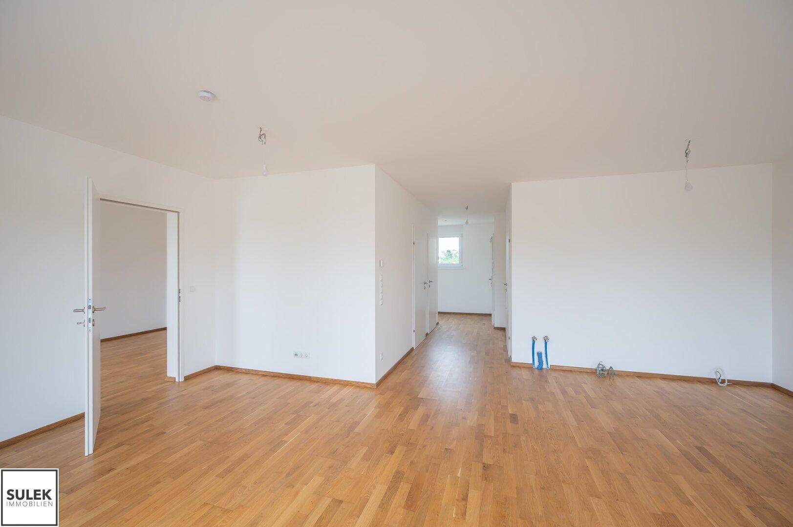 Geräumiger, heller Raum mit Parkettboden und vorbereiteten Anschlüssen, ideal für eine offene Gestaltung.