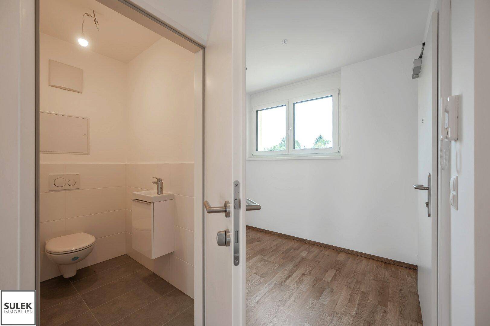 Modernes Gäste-WC mit Wand-WC, kleinem Waschbecken und Fliesenboden, praktisch und funktional.