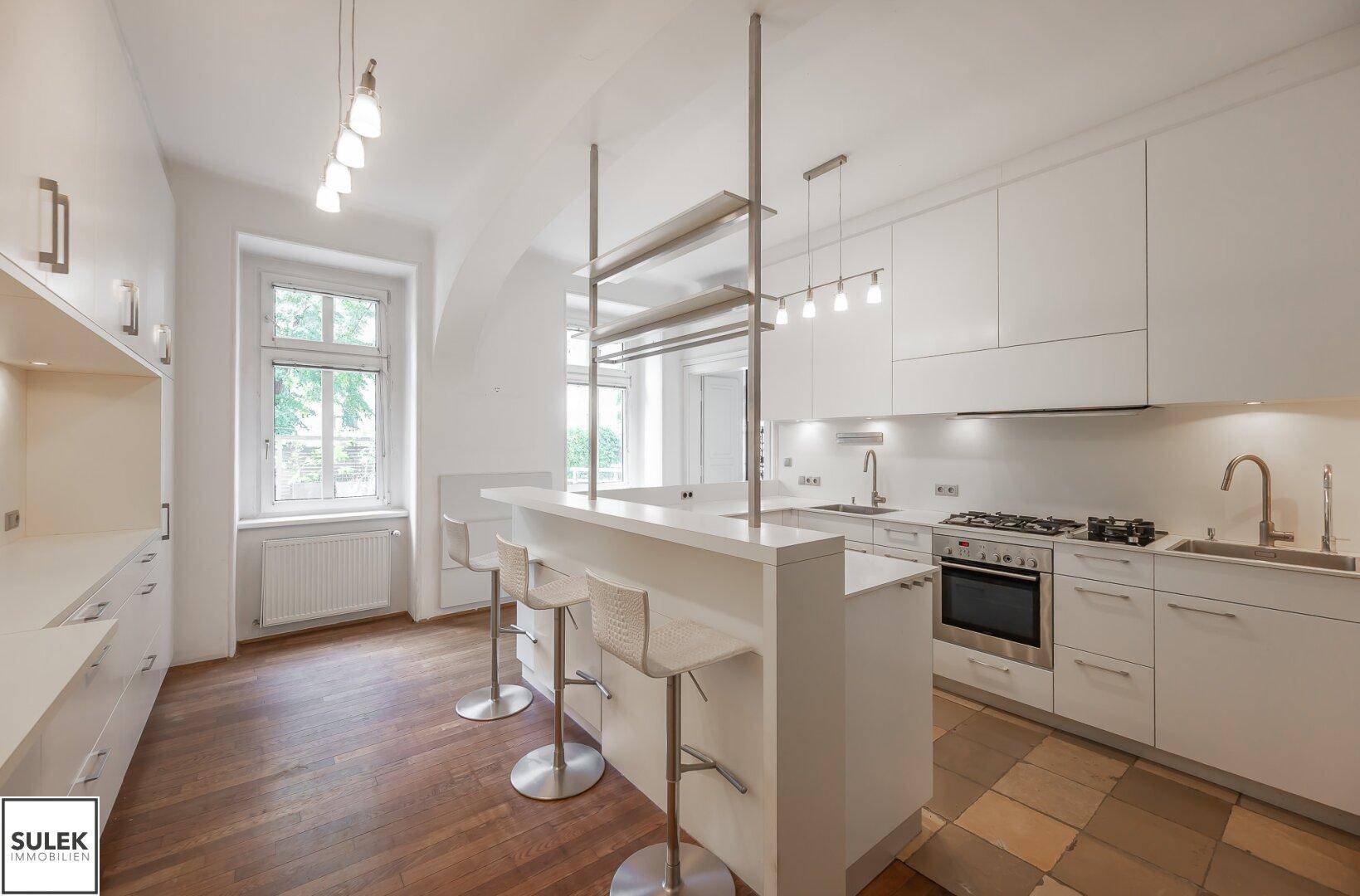 Helle moderne Küche mit Frühstücksbar, Hockern und einer Kombination aus Holz- und Fliesenboden.