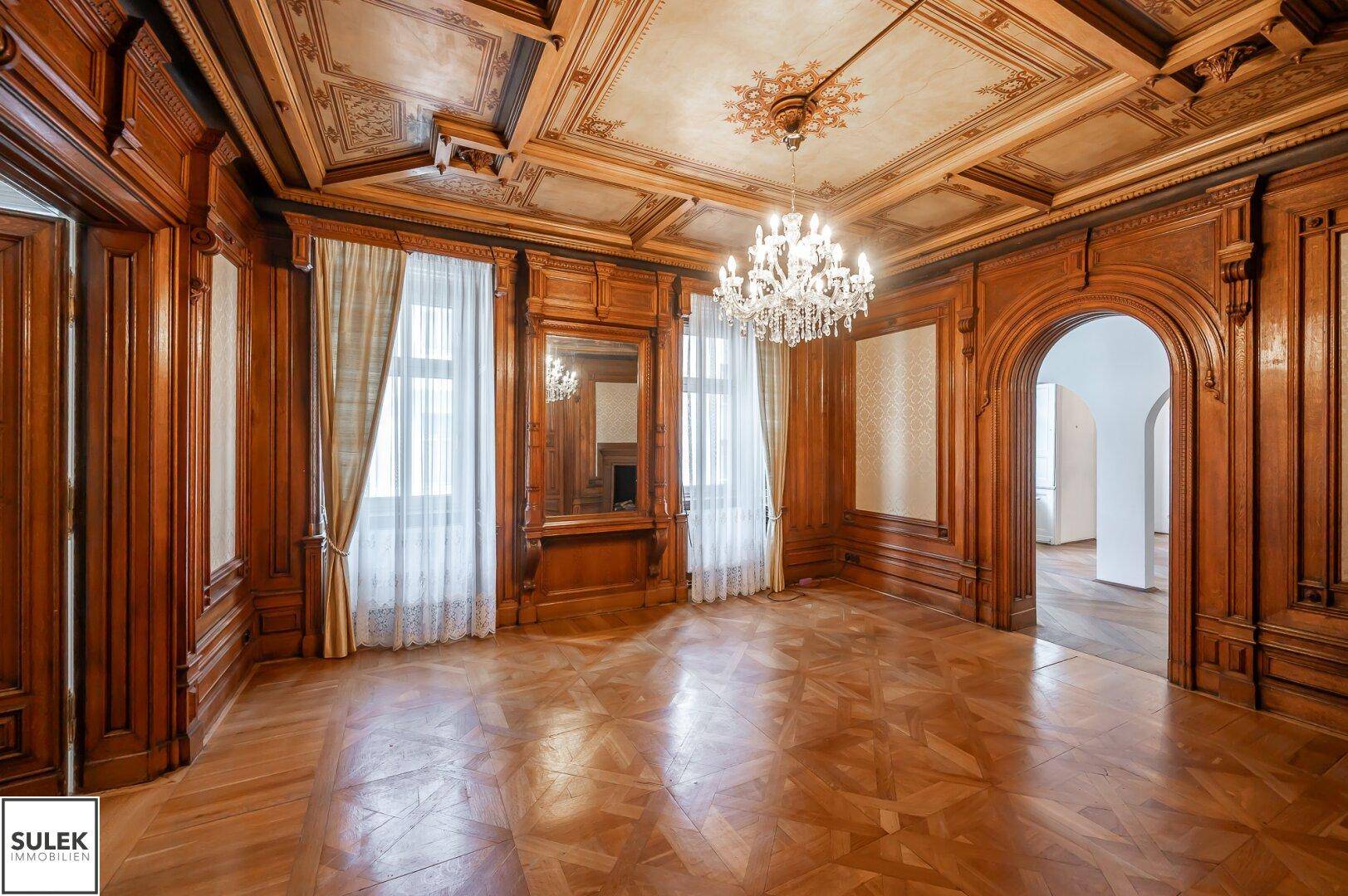 Elegantes Wohnzimmer mit dunklen Holzvertäfelungen, Fischgrätparkett und großen Fenstern.