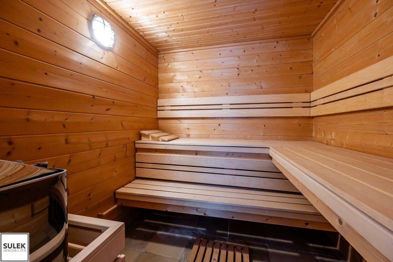 Gemütliche Holzsauna mit mehreren Bänken und einem Saunaofen für Entspannung.