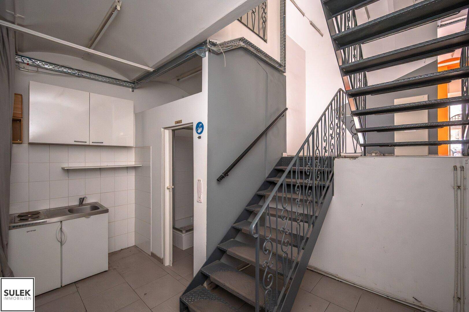 Kleiner Küchenbereich mit Spüle, Unterschrank und einem Aufzug neben der Treppe.