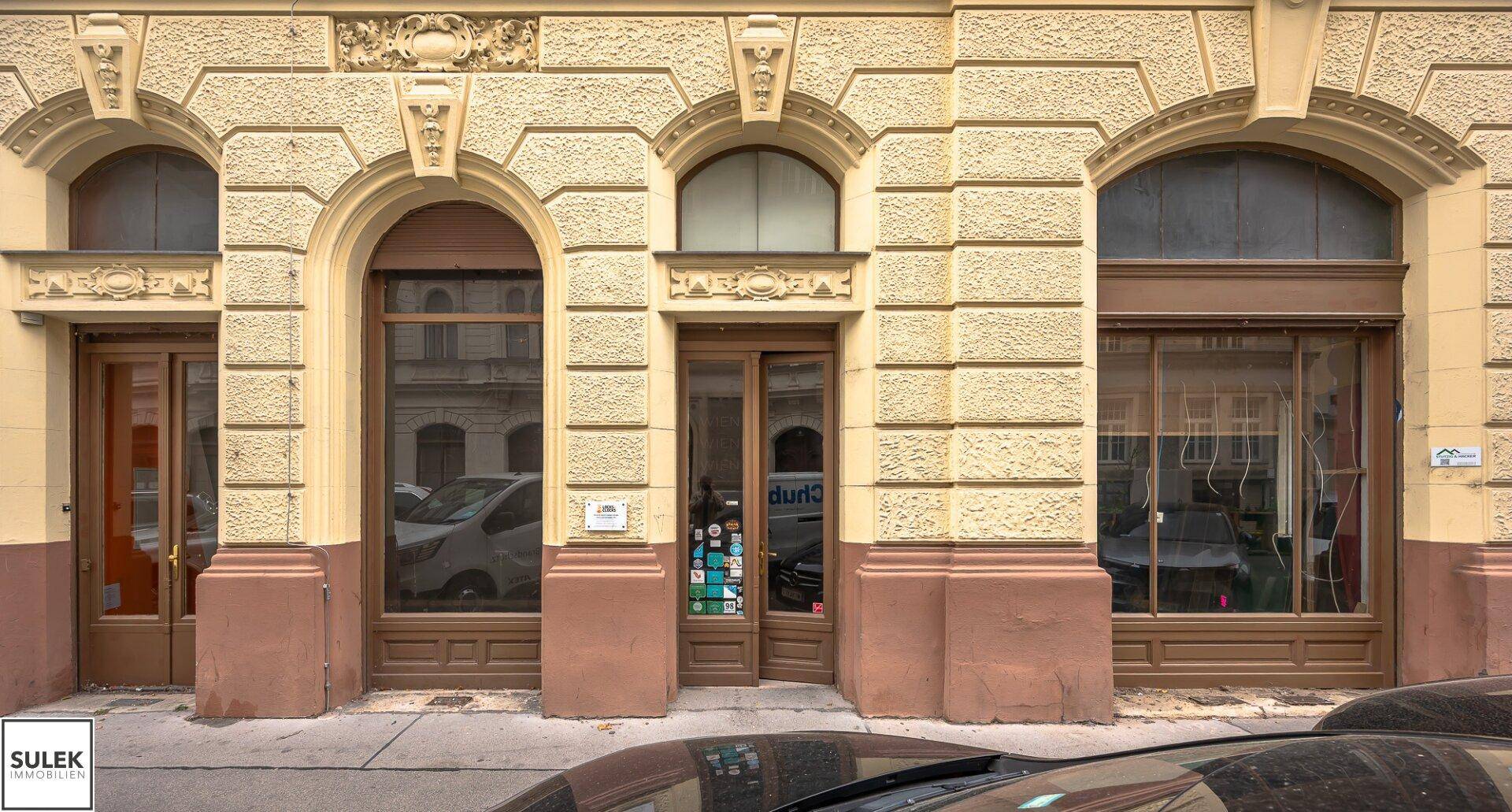 Detailansicht der historischen Fassade mit mehreren Schaufenstern und Türen auf Straßenniveau.