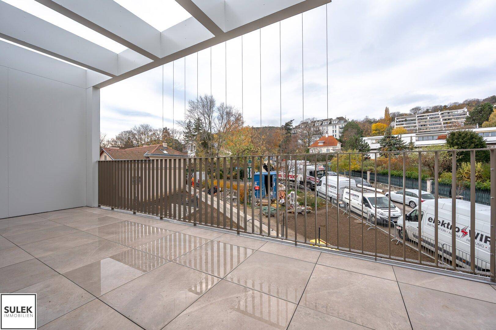 Geräumiger Balkon mit Fliesenboden und Metallgeländer, bietet einen weiten Blick auf die Umgebung.