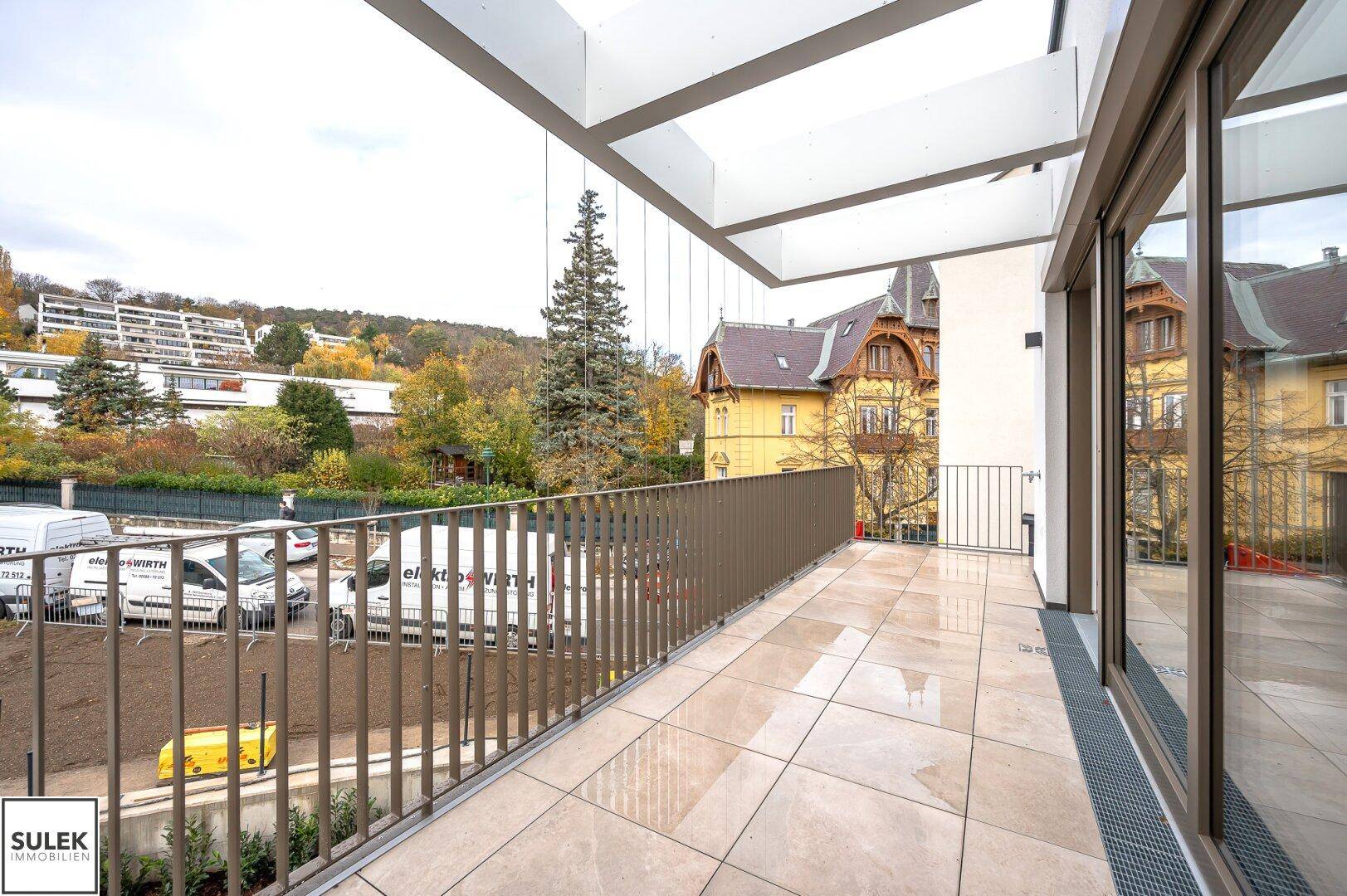 Geräumiger Balkon mit Fliesenboden und Metallgeländer, bietet einen weiten Blick auf die Umgebung.