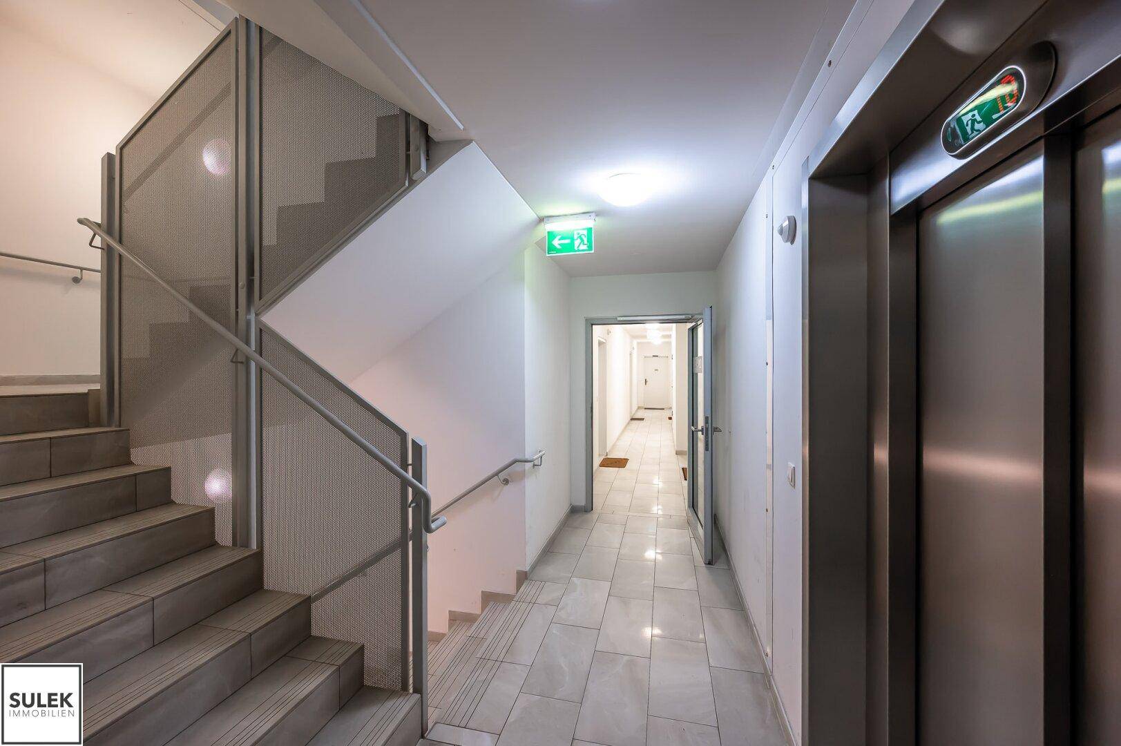 Heller Treppenaufgang und moderner Aufzug in einem gepflegten Mehrfamilienhaus.