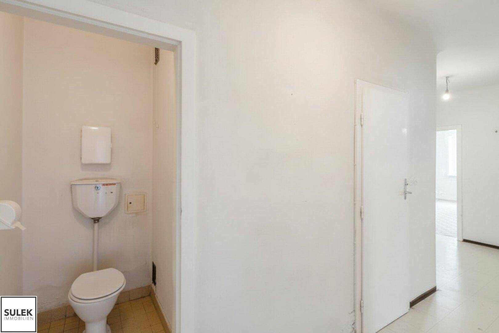 Kleines separates WC mit einfacher Ausstattung und Fliesenboden.