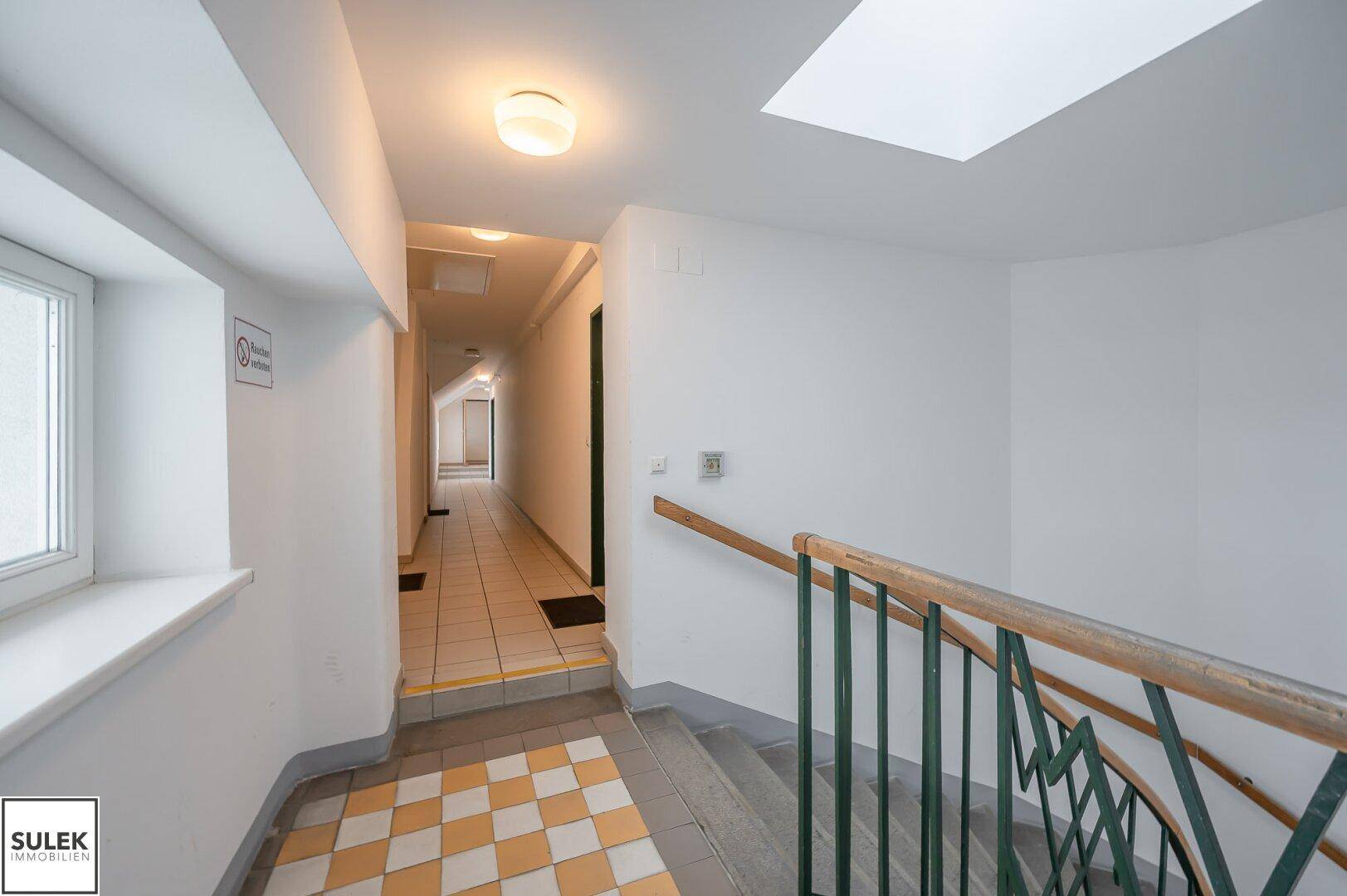 Heller Flur mit Fliesenboden, einem Oberlicht und Blick auf das Treppenhaus.