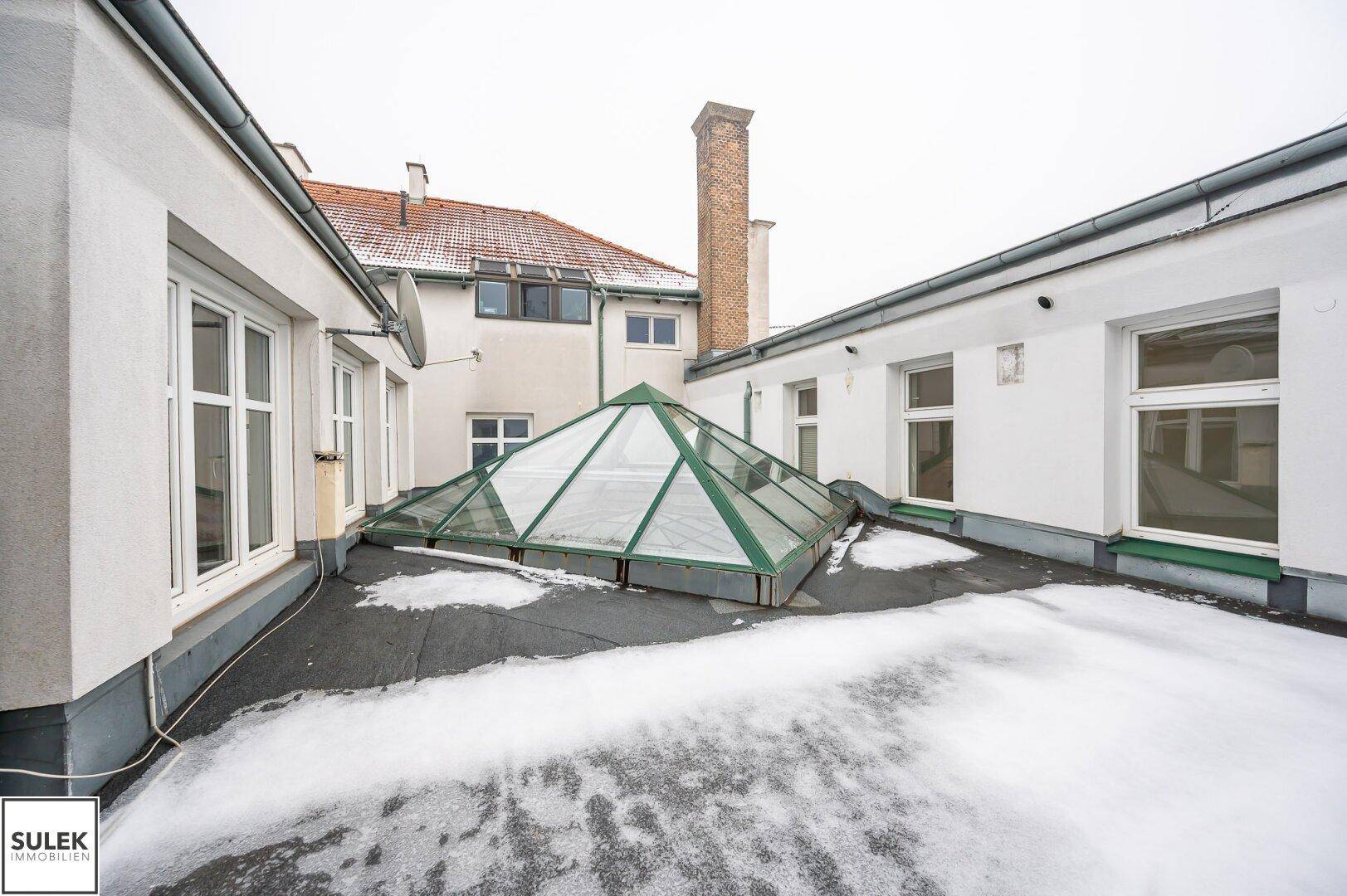 Dachterrasse mit einem großen pyramidenförmigen Oberlicht und verschneiter Oberfläche.