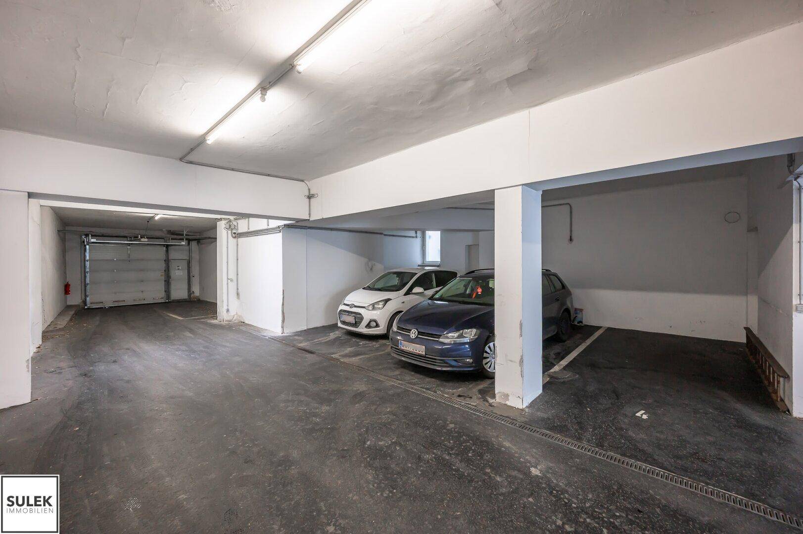Tiefgarage mit Betonboden und zwei geparkten Autos, bietet sichere Stellplätze.