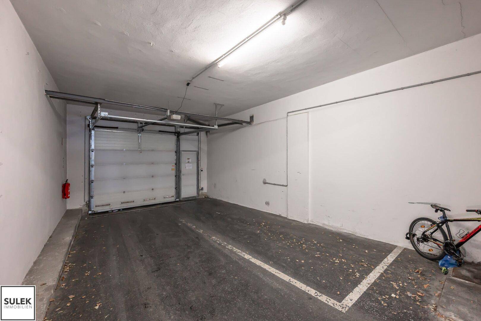 Einzelner Garagenstellplatz mit Rolltor und Betonboden, ideal für ein Fahrzeug.