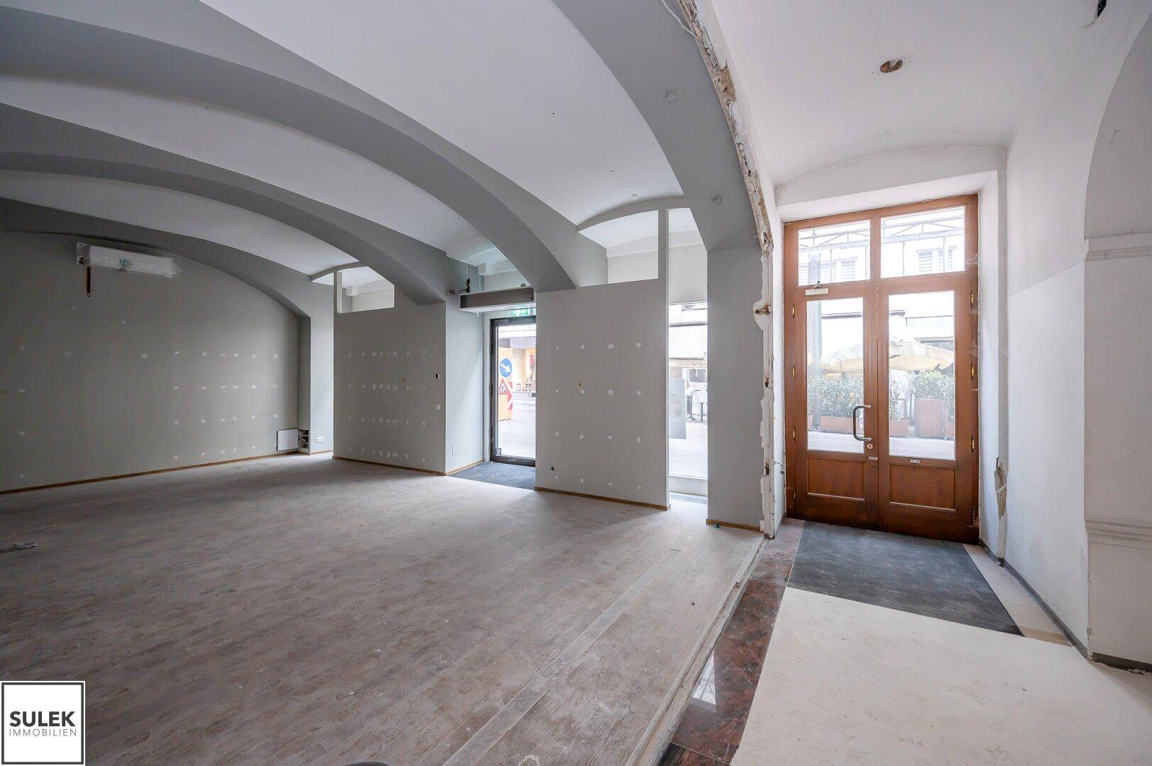 Geräumiger Gewerberaum mit beeindruckenden gewölbten Decken und großen Fenstern, bereit für den Innenausbau.