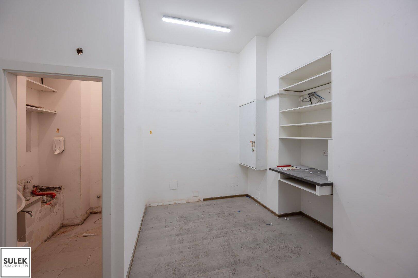 Funktionaler Nebenraum mit praktischen Regalen und vorbereiteten Anschlüssen, ideal als Lager oder kleines Büro.