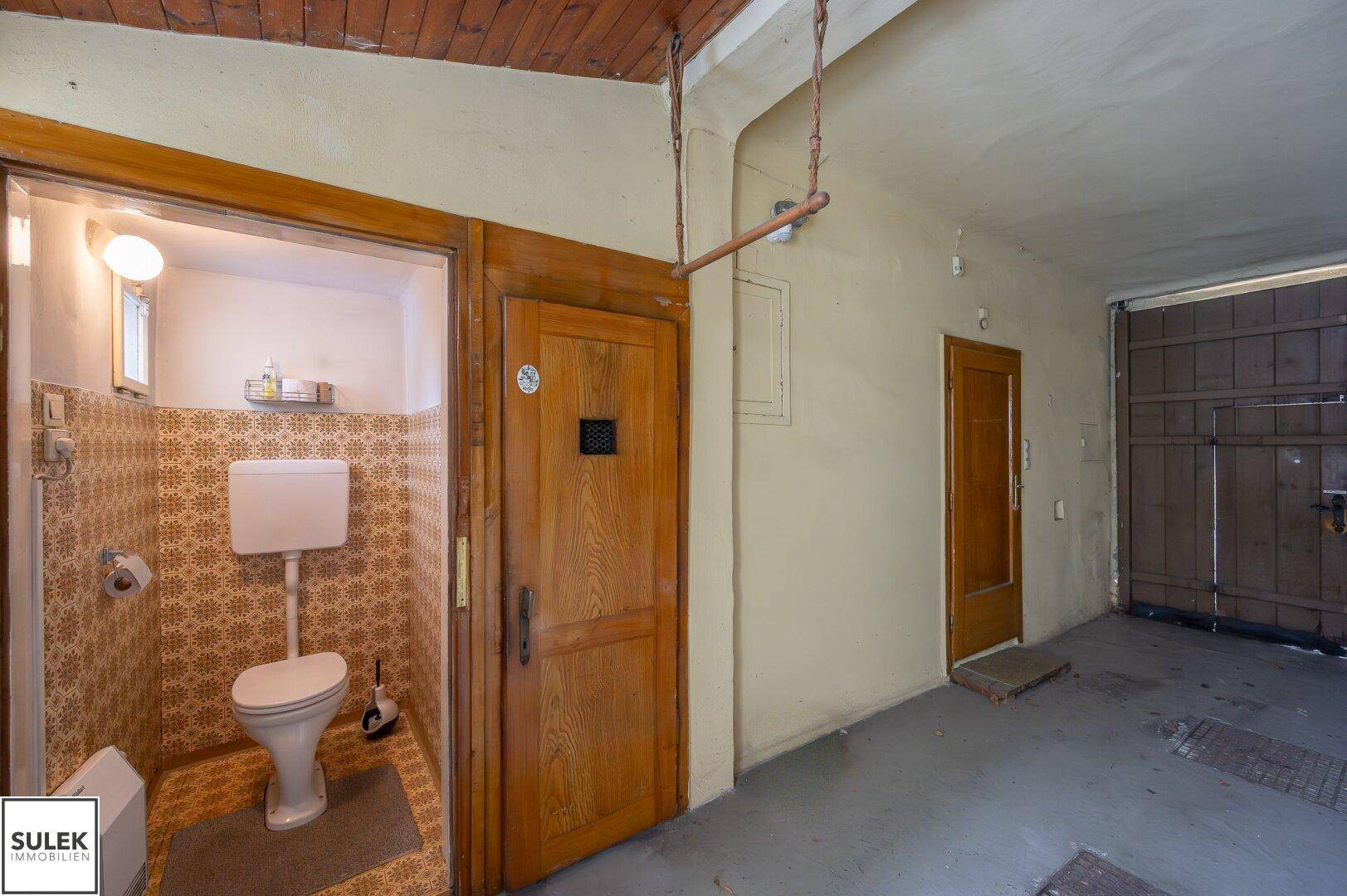 Kleine Gästetoilette mit gemusterten Fliesen und einfacher Ausstattung im Durchgangsbereich.