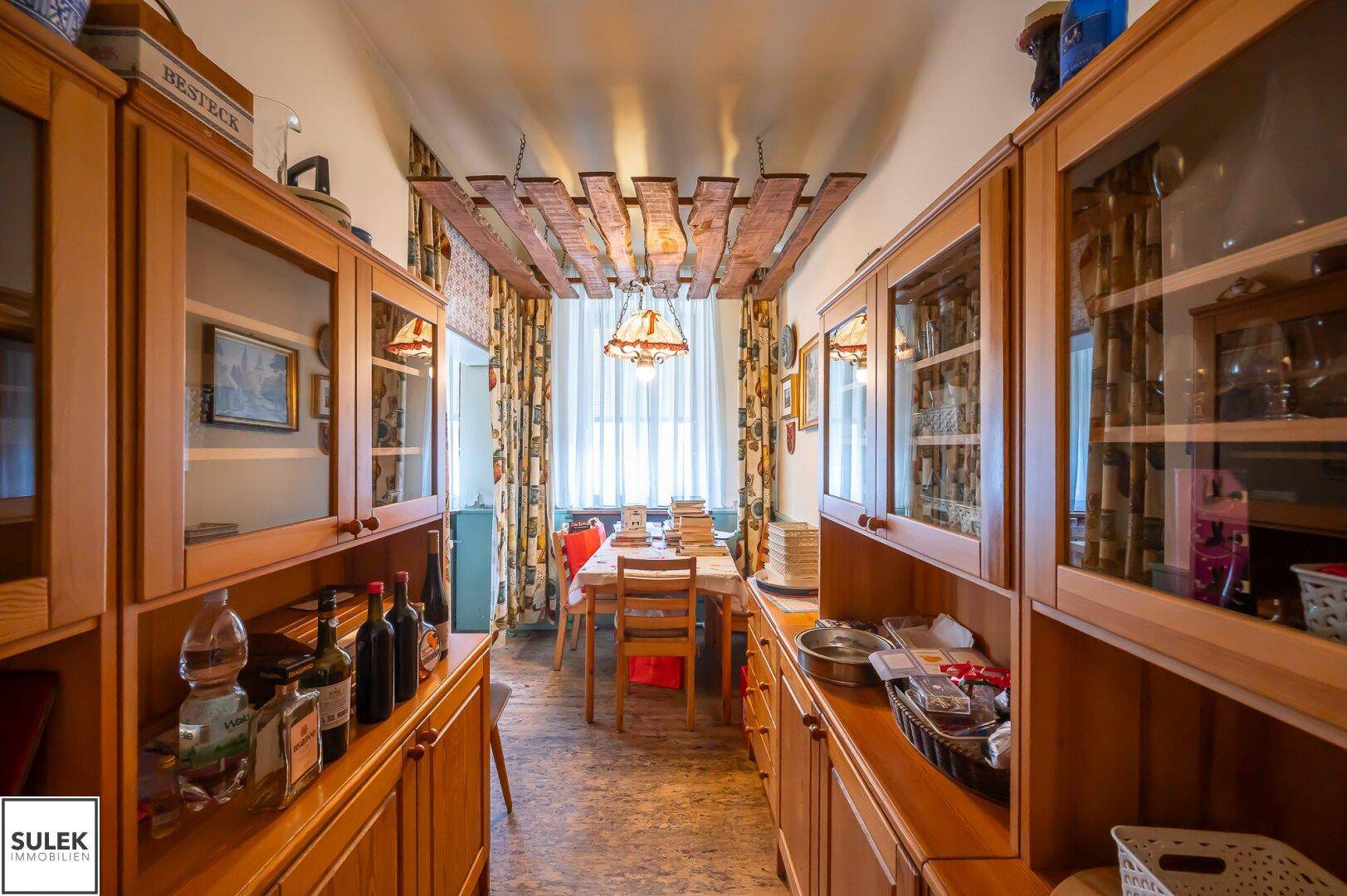 Esszimmer mit Holzschränken, Esstisch und einer Deckenverkleidung aus Holzlatten.