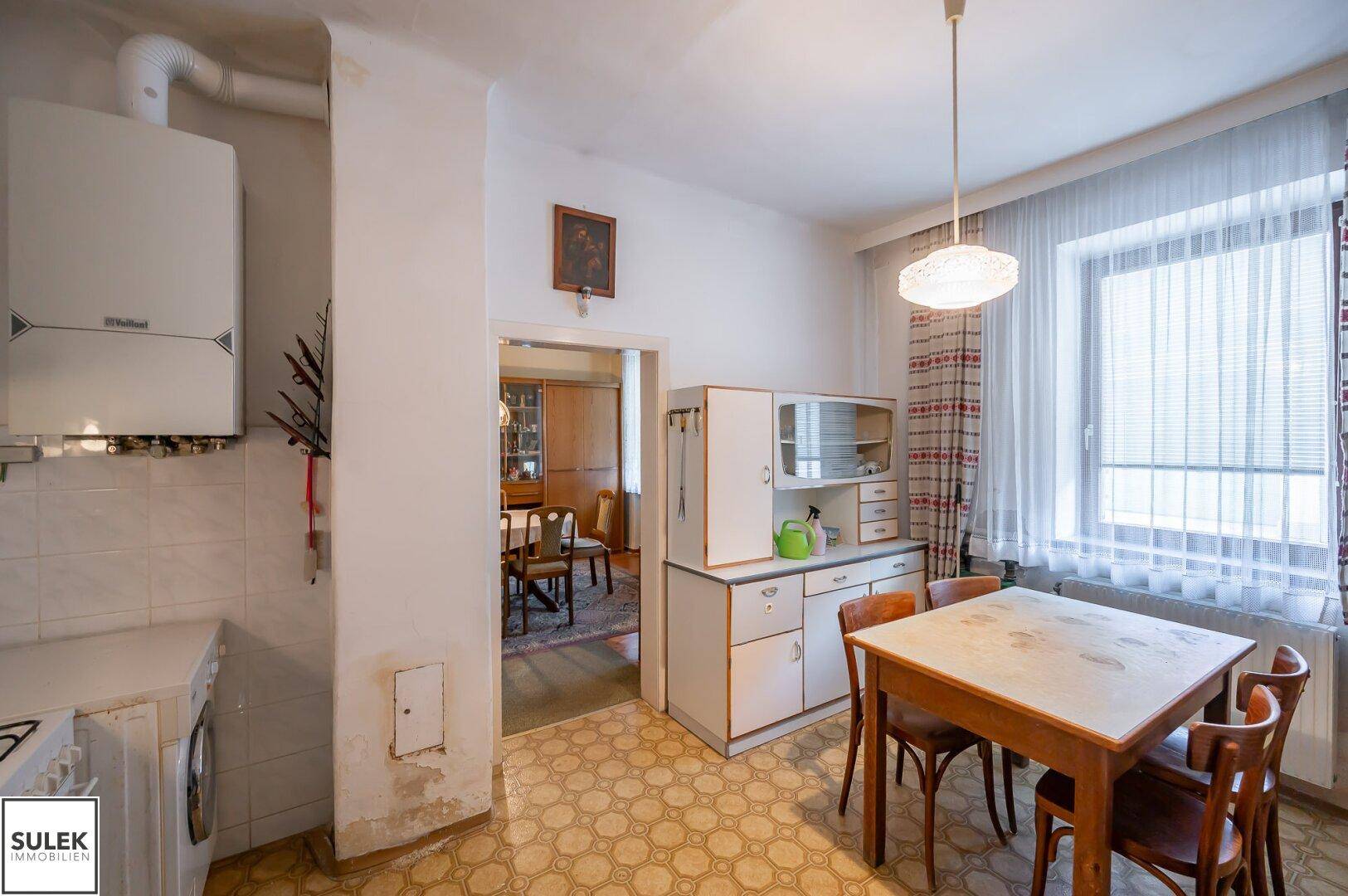 Küche mit Esstisch, Fenster und Blick auf den angrenzenden Essbereich.