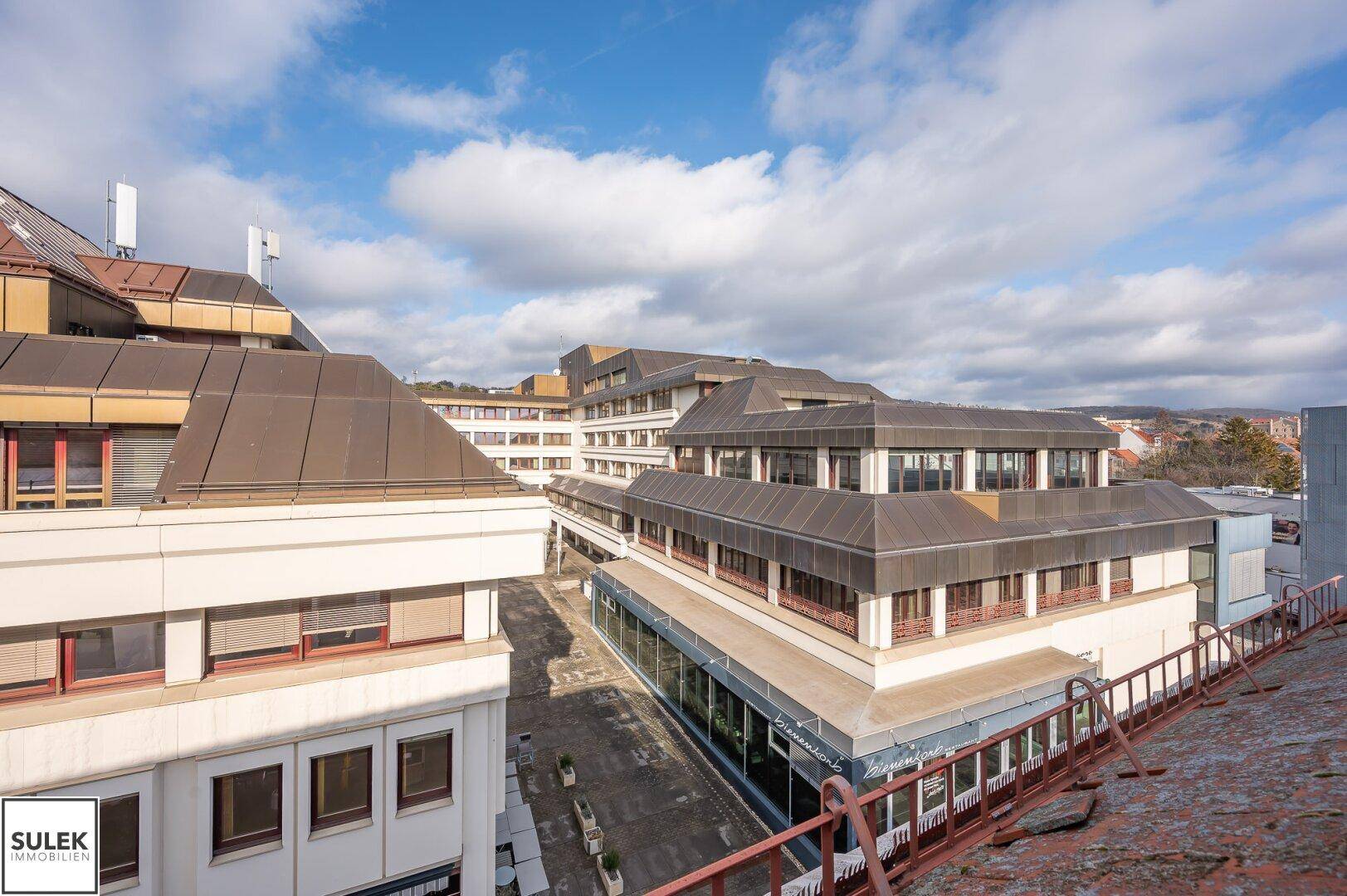 Panoramablick über eine städtische Bebauung mit vielen Dächern und Gebäuden.