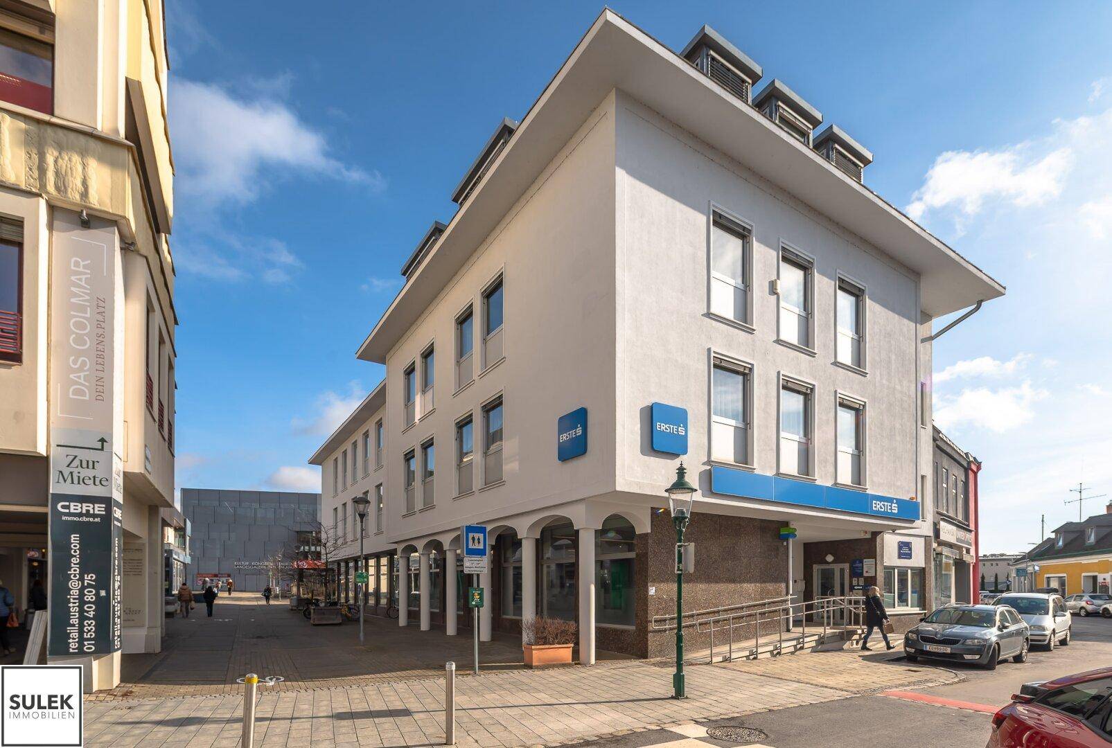 Modernes Geschäftsgebäude an einer Straßenecke mit Bankfiliale im Erdgeschoss.