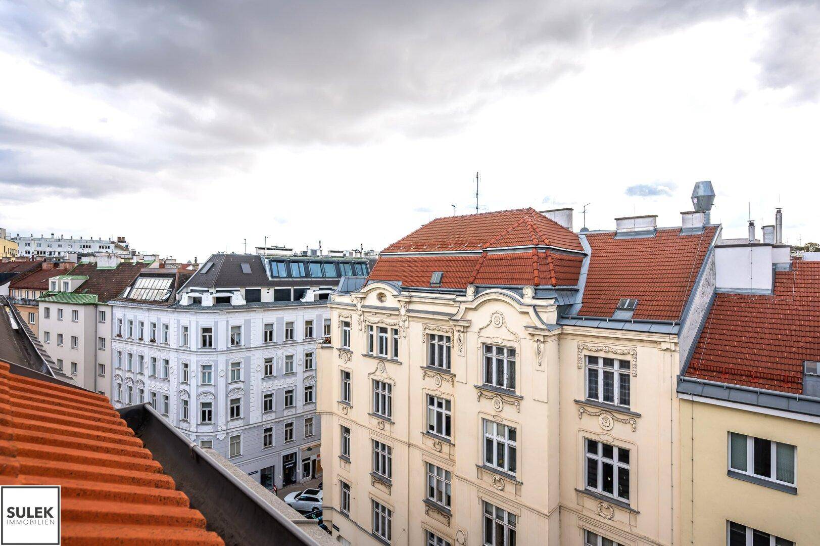 Panoramablick über die Dächer der Stadt mit historischen Gebäuden und einem bewölkten Himmel.
