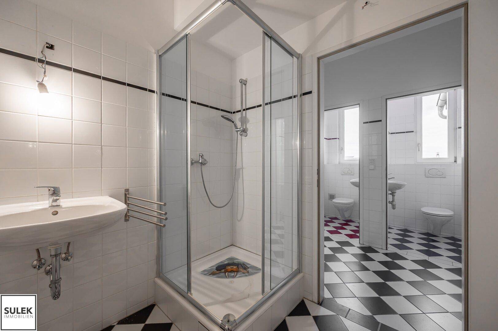 Modernes Badezimmer mit Duschkabine, Waschbecken und schwarz-weiß gefliestem Boden.