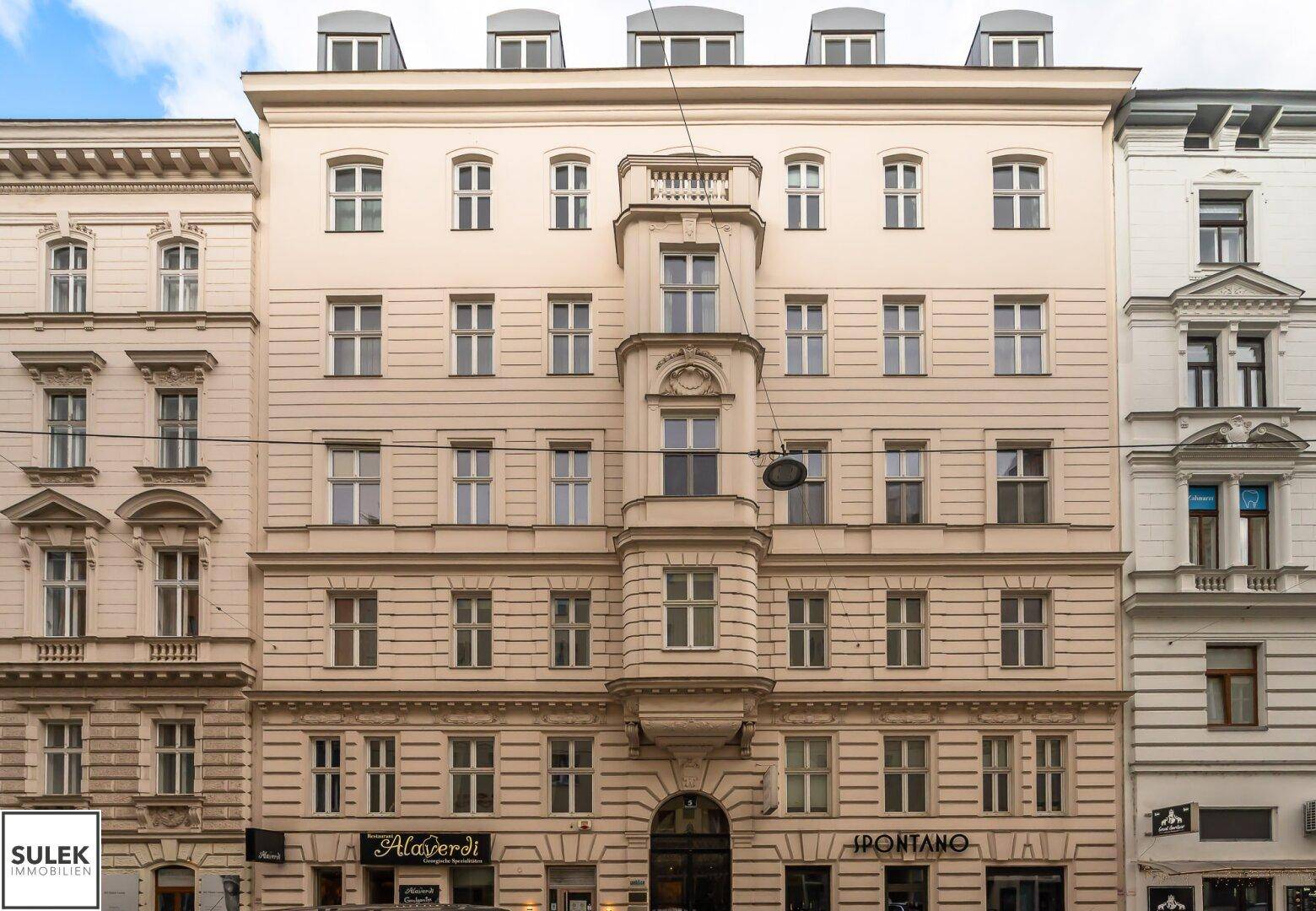 Historische Fassade eines Mehrfamilienhauses mit vielen Fenstern und klassischer Architektur.