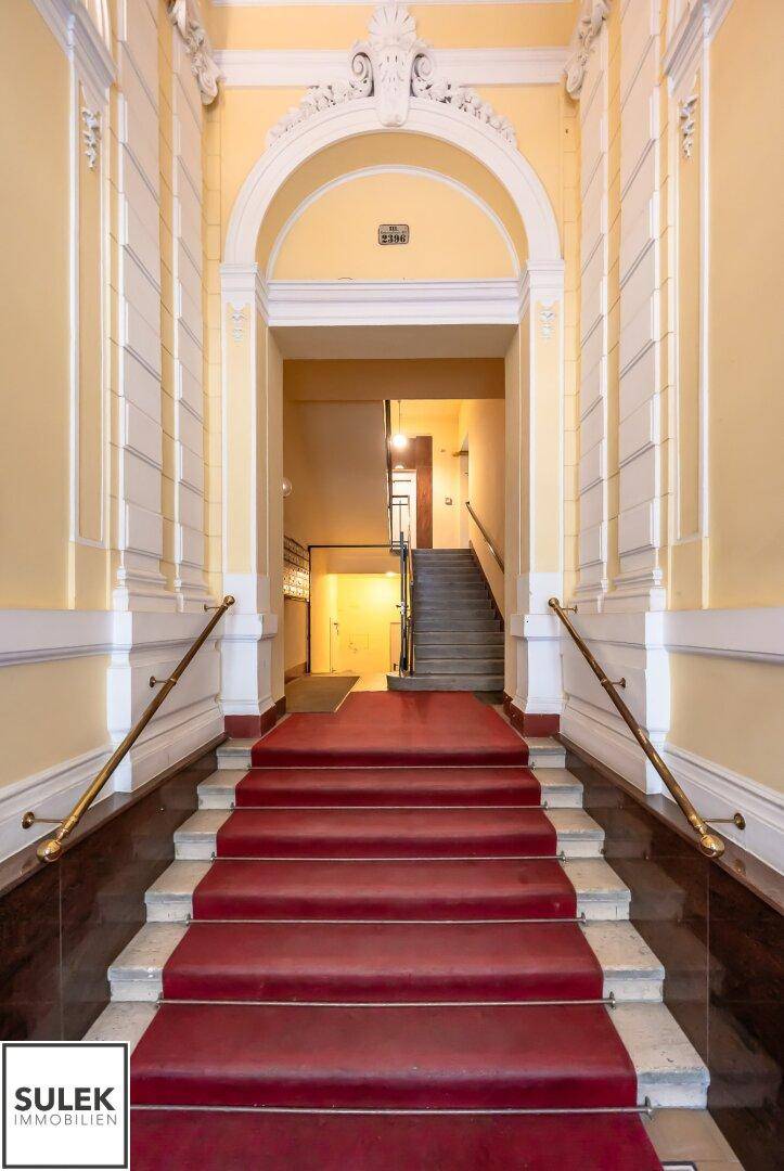 Prunkvoller Eingangsbereich mit rotem Teppich auf der Treppe und klassischer Architektur.