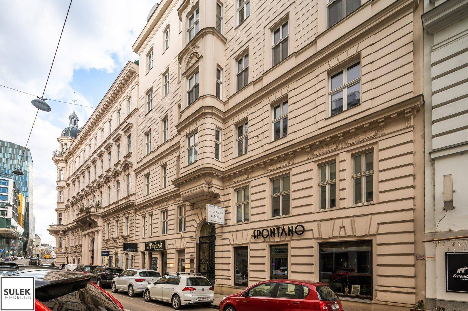 Elegante Straßenansicht eines historischen Gebäudes mit Geschäften im Erdgeschoss und klassischer Architektur.