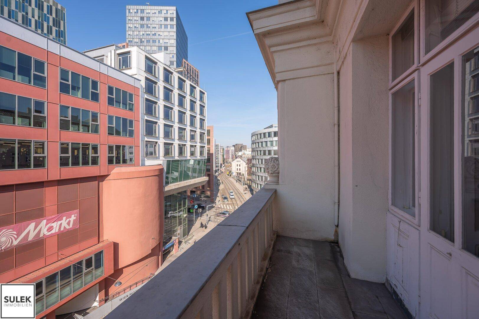 Balkon mit Steinboden und weitem Blick auf die moderne Stadtarchitektur und belebte Straße.