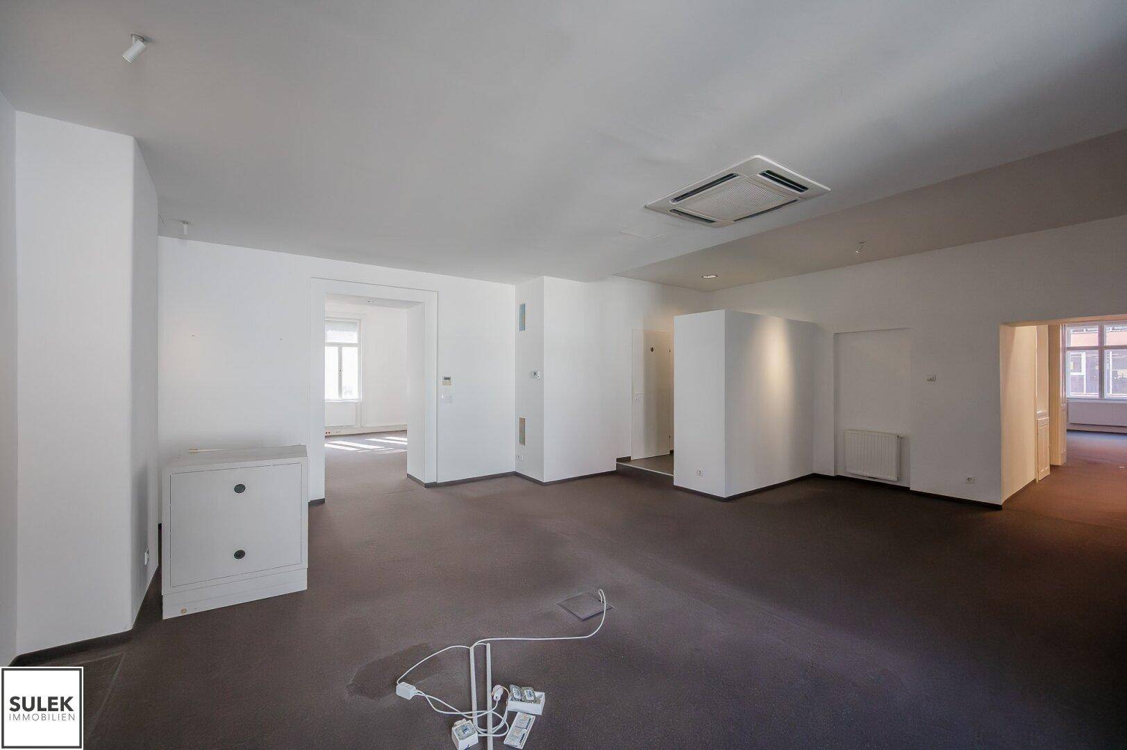 Großer Büroraum mit Teppichboden, Klimaanlage und offenem Grundriss.