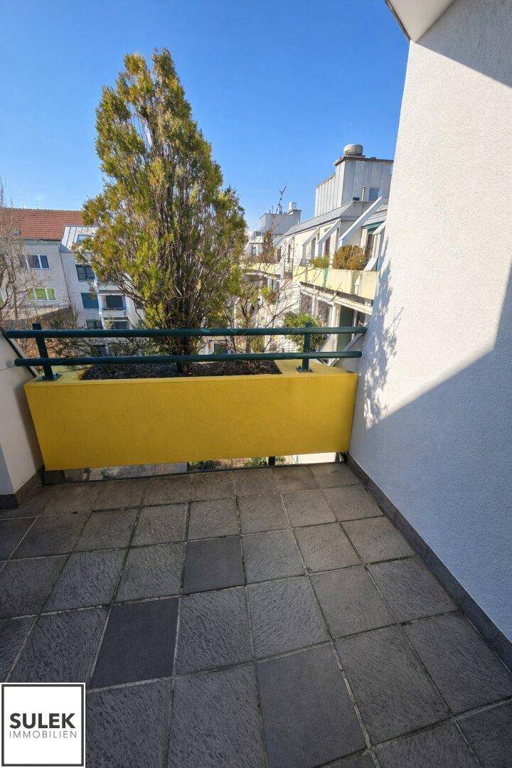 Heller Balkon mit Fliesenboden und gelben Pflanzkästen, ideal für entspannte Stunden im Freien.