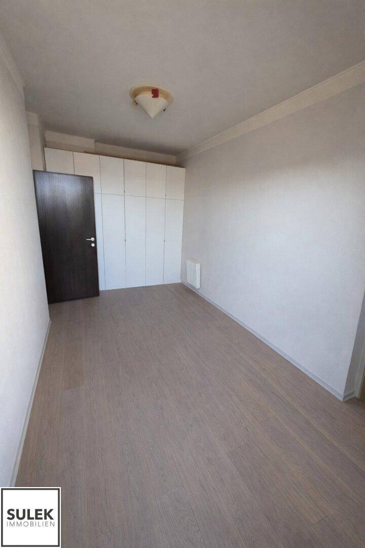 Helles Zimmer mit Laminatboden und integrierten weißen Kleiderschränken, ideal als Schlafzimmer.